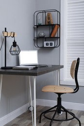 Comfortable workplace with modern laptop near light grey wall indoors