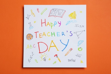 Paper with inscription HAPPY TEACHER'S DAY on orange background, top view