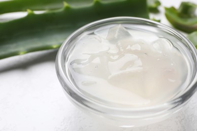 Photo of Aloe vera gel in bowl on white background, closeup. Space for text