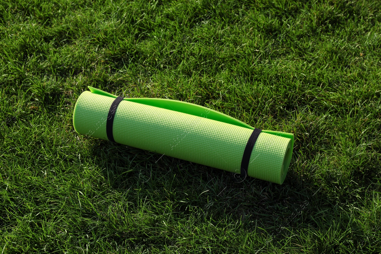 Photo of Bright exercise mat on fresh green grass outdoors