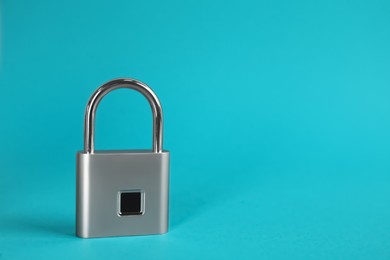 Photo of Modern padlock on light blue background. Space for text