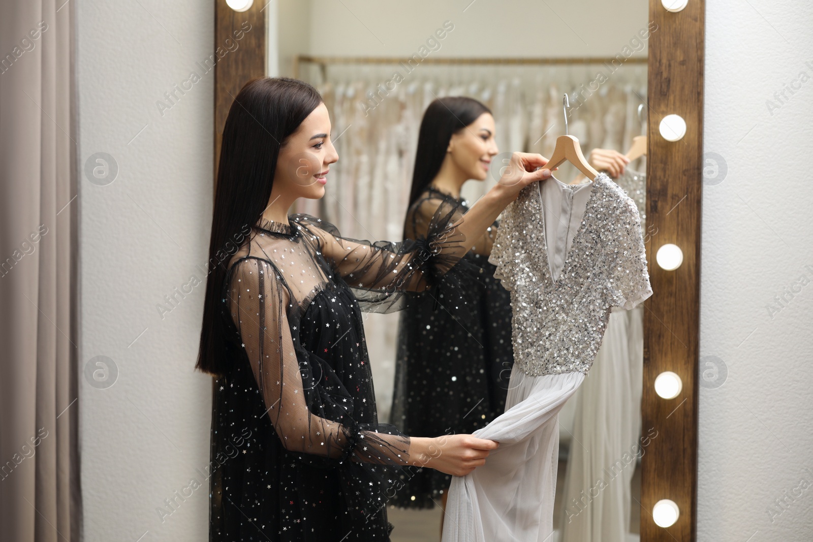 Photo of Woman choosing dress in rental clothing salon