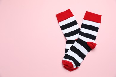 Photo of Striped socks on light pink background, flat lay. Space for text