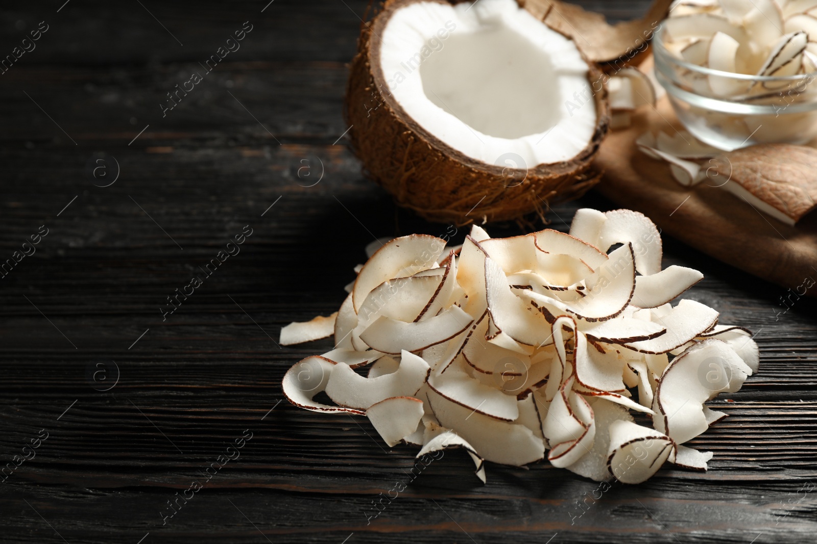 Photo of Pile of tasty coconut chips on black wooden table