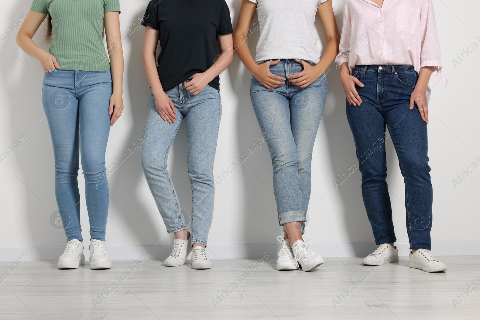 Photo of Women in stylish jeans near white wall, closeup