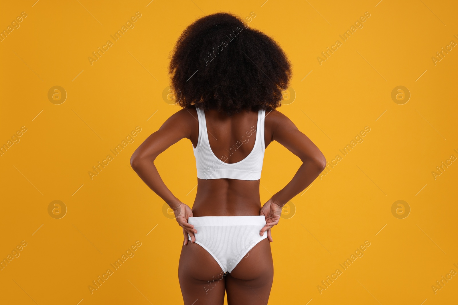 Photo of Woman in stylish bikini on yellow background, back view
