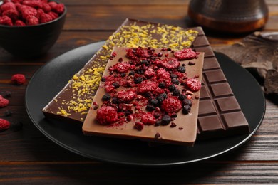 Chocolate bars with freeze dried fruits on wooden table, closeup