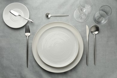 Photo of Stylish setting with cutlery, glasses and plates on grey table, flat lay