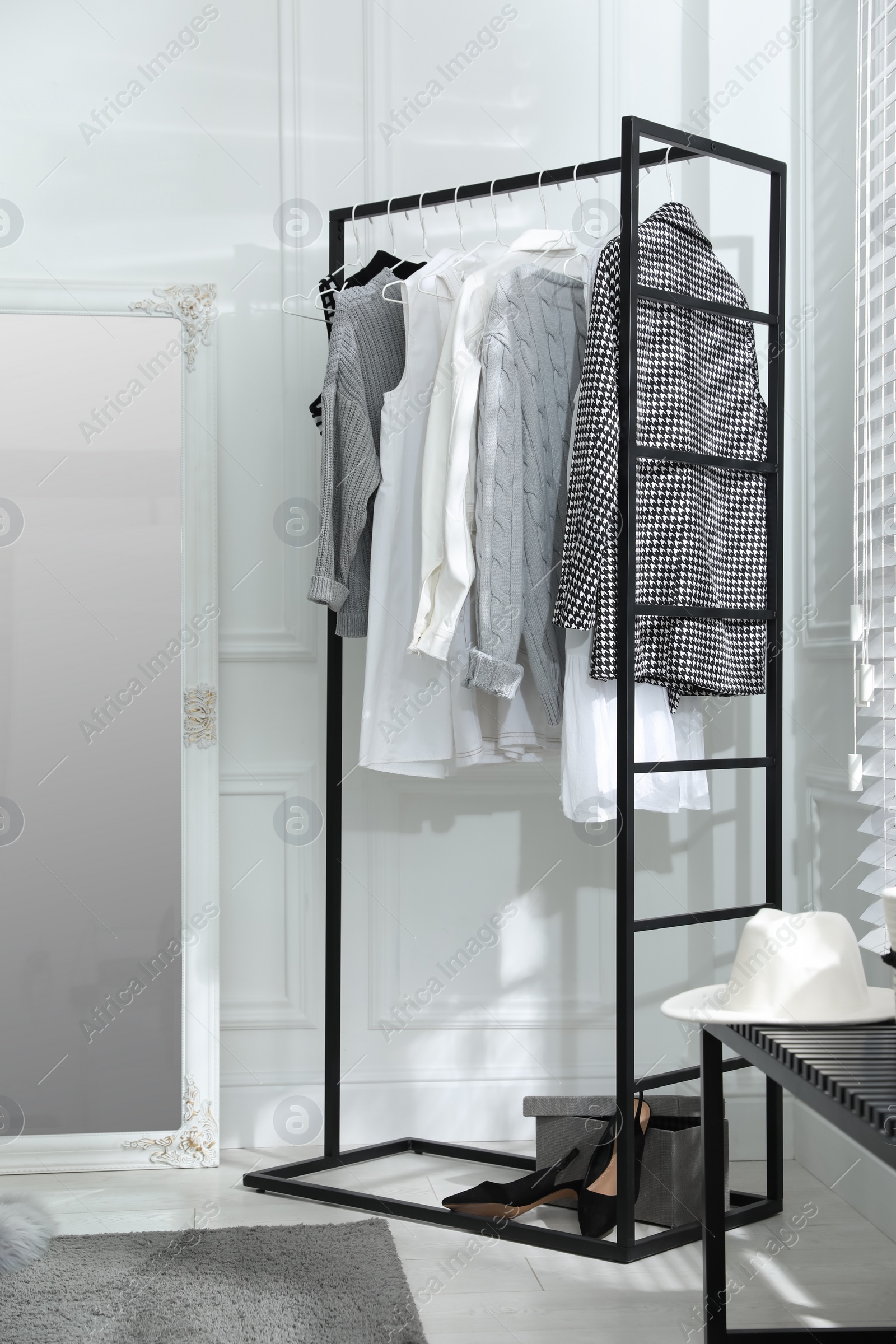 Photo of Rack with stylish women's clothes and large mirror in dressing room. Interior design