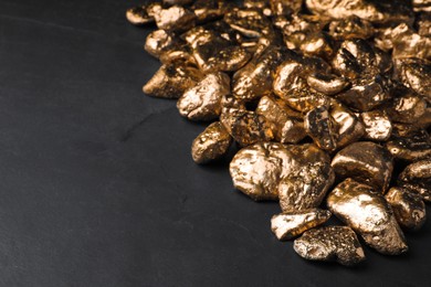 Photo of Pile of gold nuggets on black table, space for text