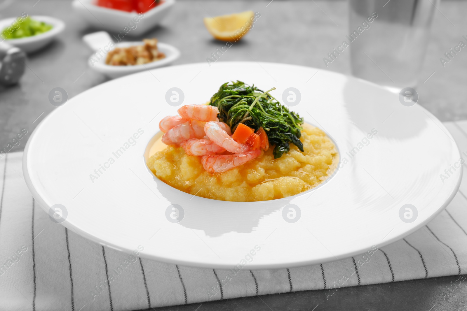 Photo of Plate with fresh tasty shrimp and grits on table