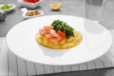 Photo of Plate with fresh tasty shrimp and grits on table