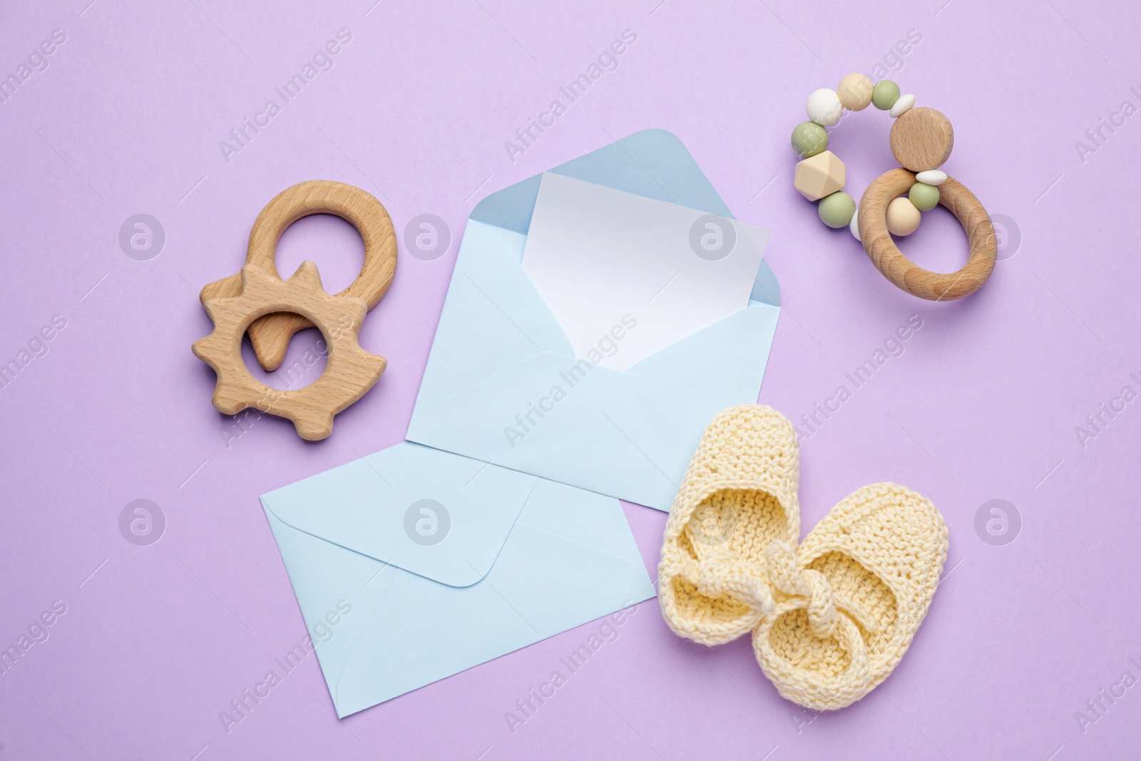 Photo of Envelopes for baby shower and accessories on lilac background, flat lay