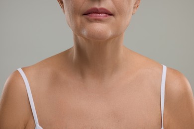 Mature woman with healthy skin on grey background, closeup