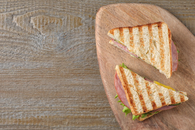 Photo of Tasty sandwich with ham on wooden table, top view. Space for text