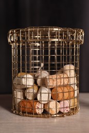 Photo of Metal basket with corks on rack against black background