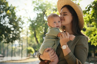 Young mother with her cute baby in park on sunny day