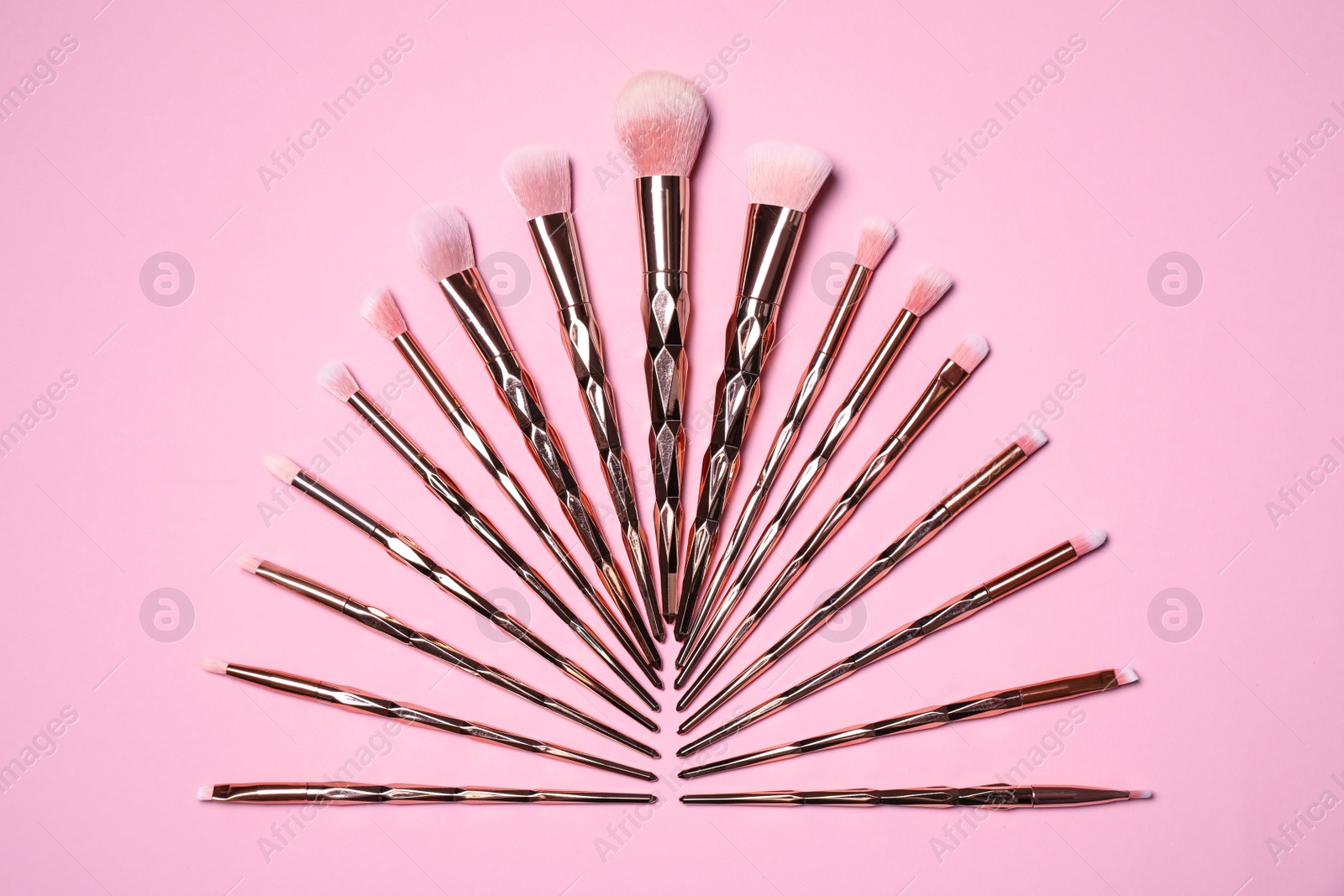 Photo of Set of makeup brushes on pink background, flat lay