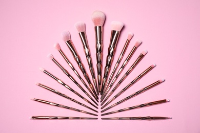 Set of makeup brushes on pink background, flat lay