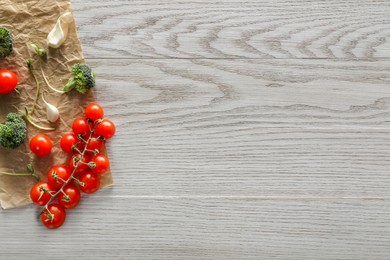 Food photography. Fresh cherry tomatoes, broccoli, garlic and microgreen on wooden table, flat lay with space for text