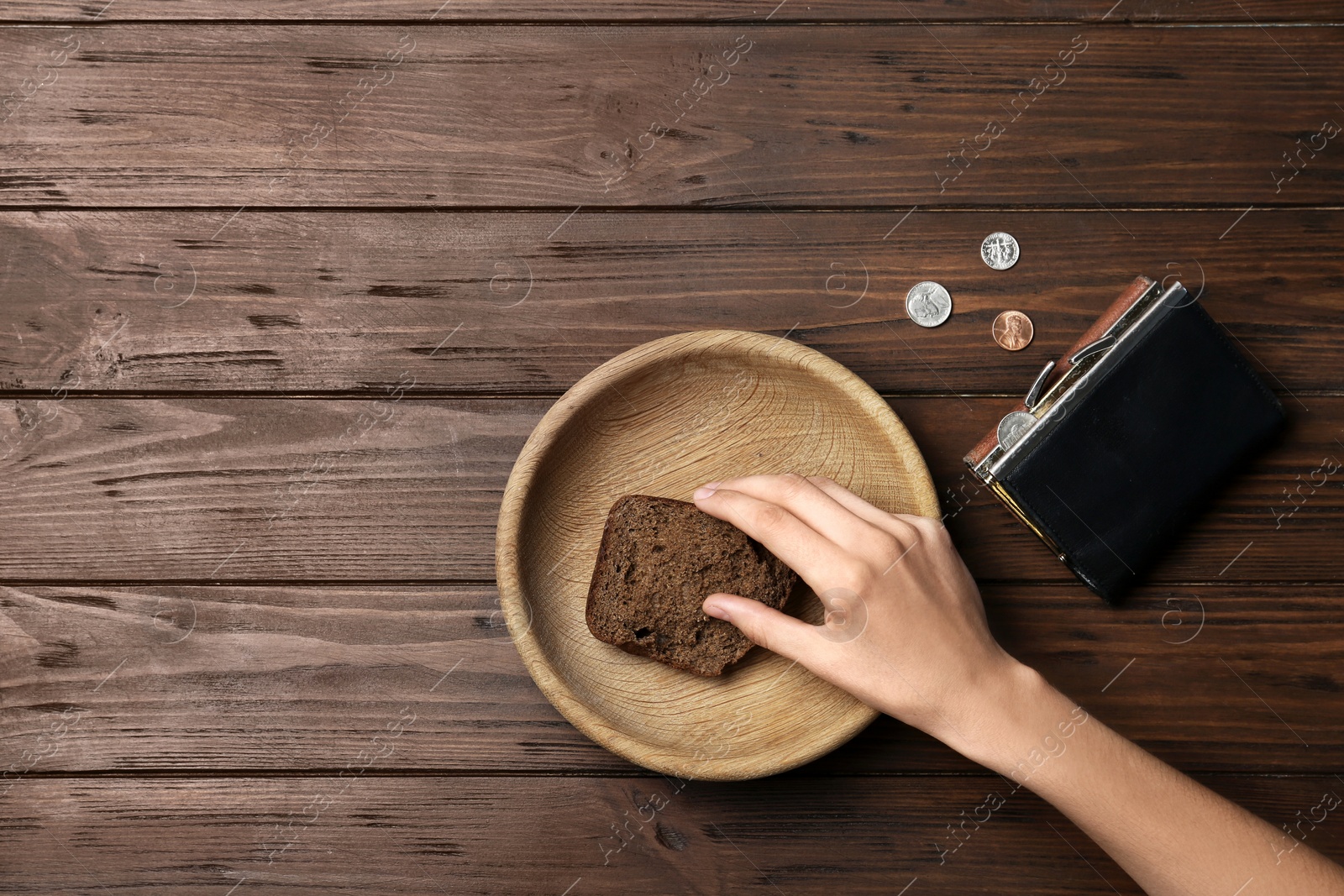 Photo of Poor woman with rye bread, wallet and coins at wooden table, space for text