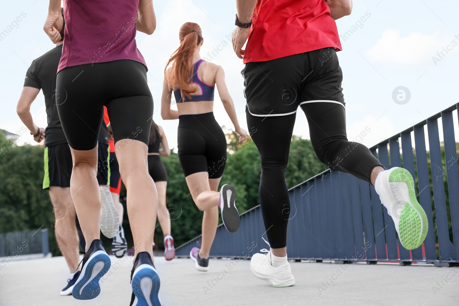 Photo of Group of people running outdoors, back view