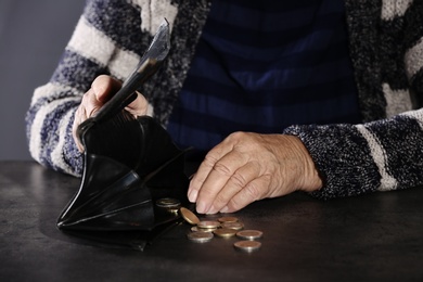 Poor elderly woman counting coins at table, closeup