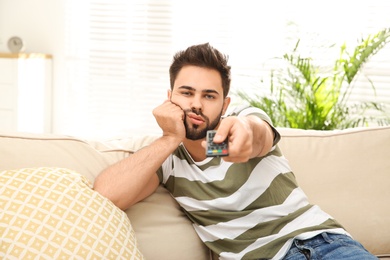 Lazy young man watching TV on sofa at home