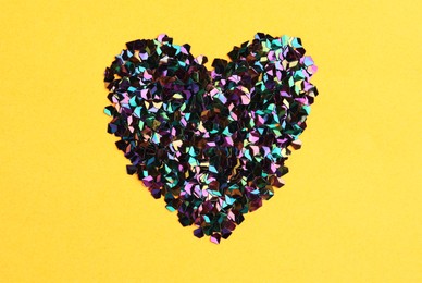 Photo of Heart made with shiny glitter on yellow background, flat lay
