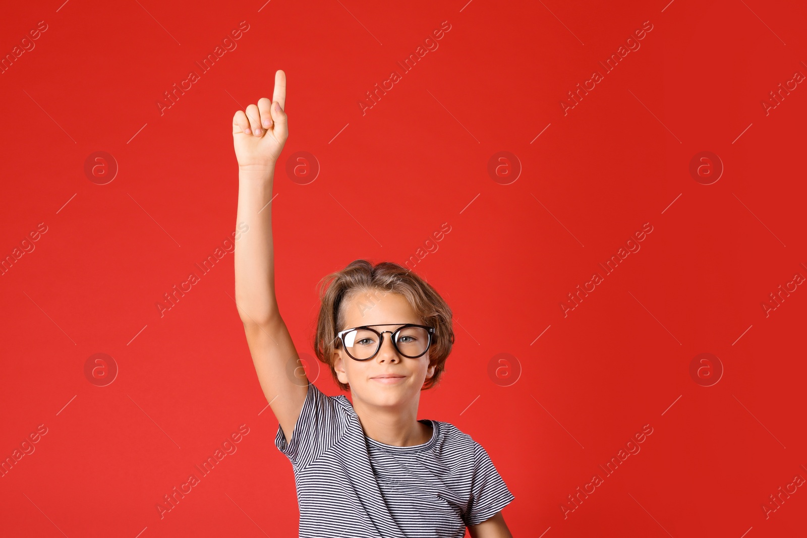 Photo of Cute little boy in casual outfit on red background