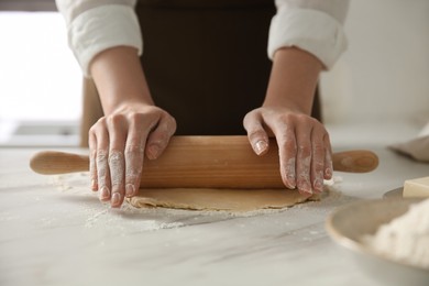 Photo of Woman rolling dough at table in kitchen, closeup