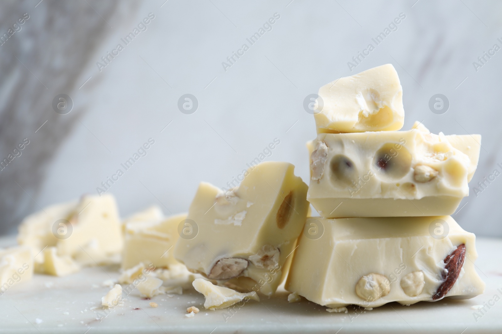 Photo of Pieces of white chocolate with nuts on table. Space for text