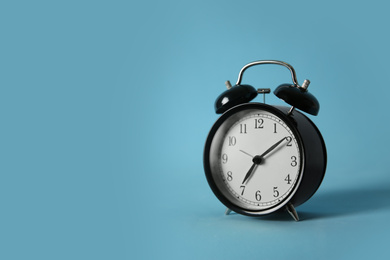 Photo of Alarm clock on light blue background, space for text. Morning time