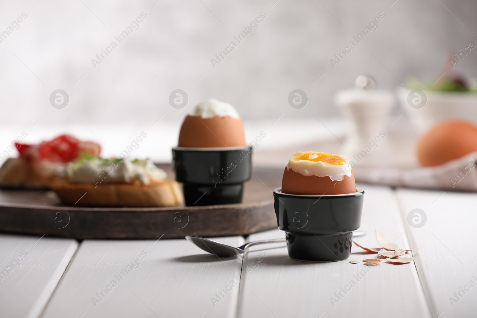 Photo of Fresh soft boiled egg in cup served on white wooden table. Space for text