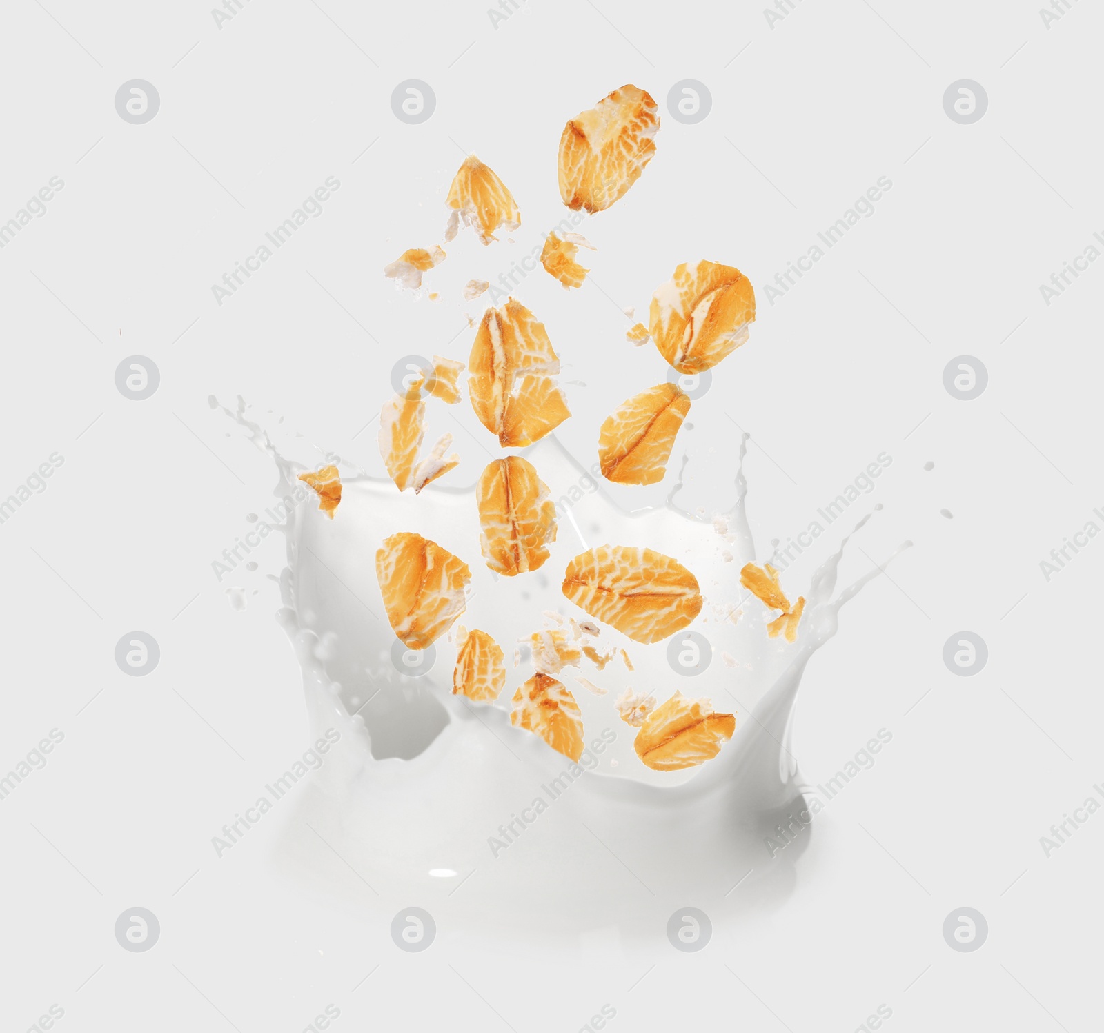 Image of Rolled oats falling into splashing milk on white background