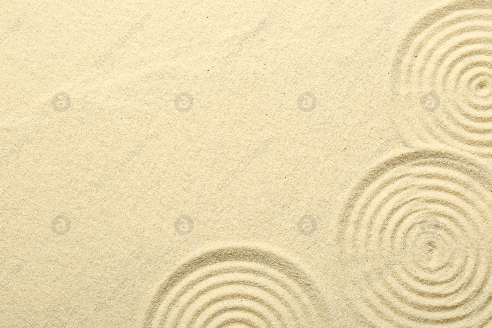 Photo of Zen rock garden. Circle patterns on beige sand, top view