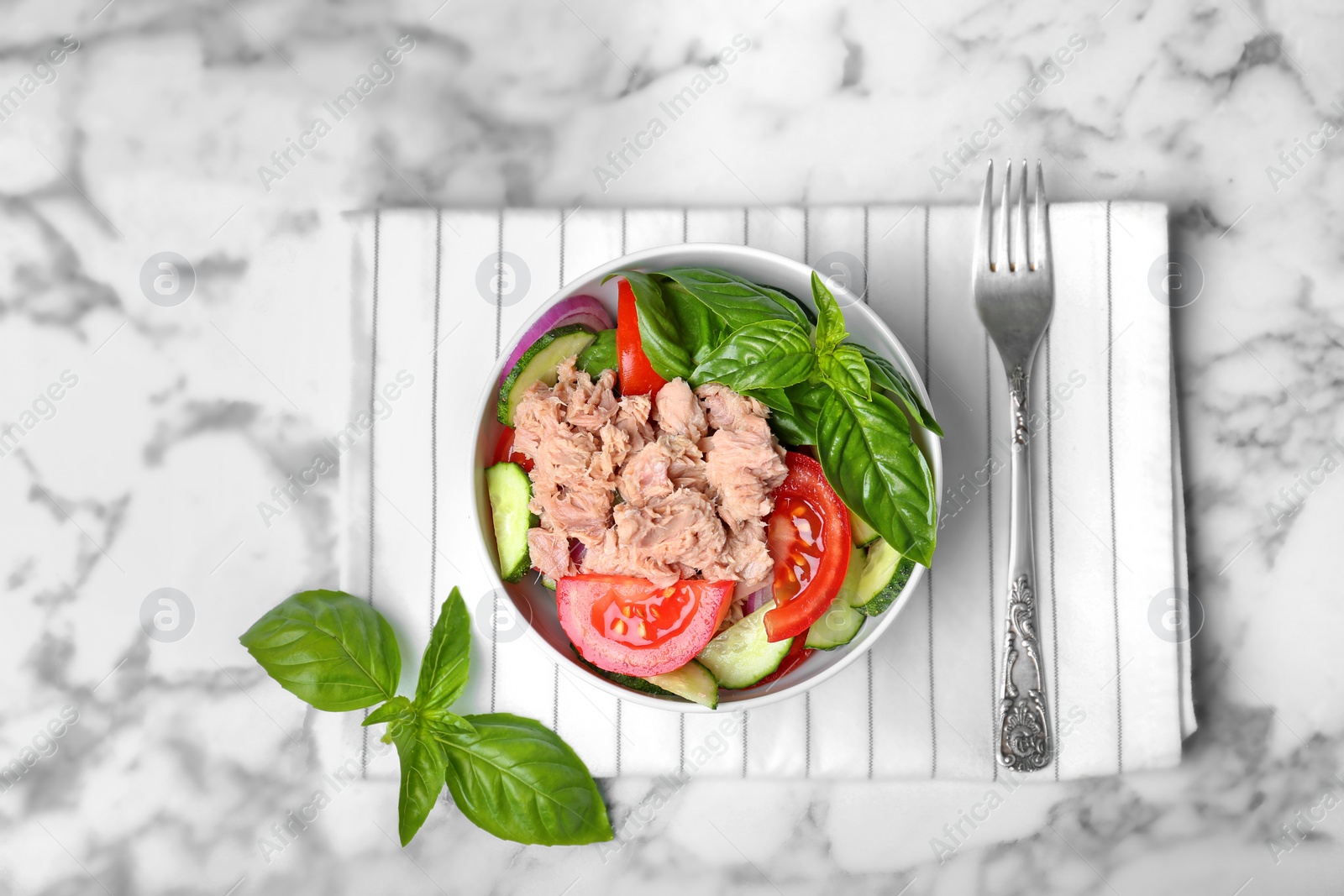 Photo of Delicious salad with canned tuna in bowl on marble background, top view