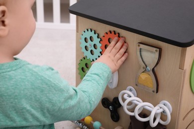 Little child playing with busy board house indoors, closeup