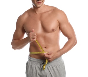 Photo of Young man with slim body using measuring tape on white background, closeup view