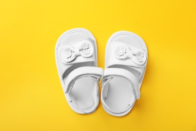 Pair of cute baby sandals on color background, top view