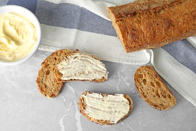 Photo of Tasty bread with butter served for breakfast on grey marble table, top view