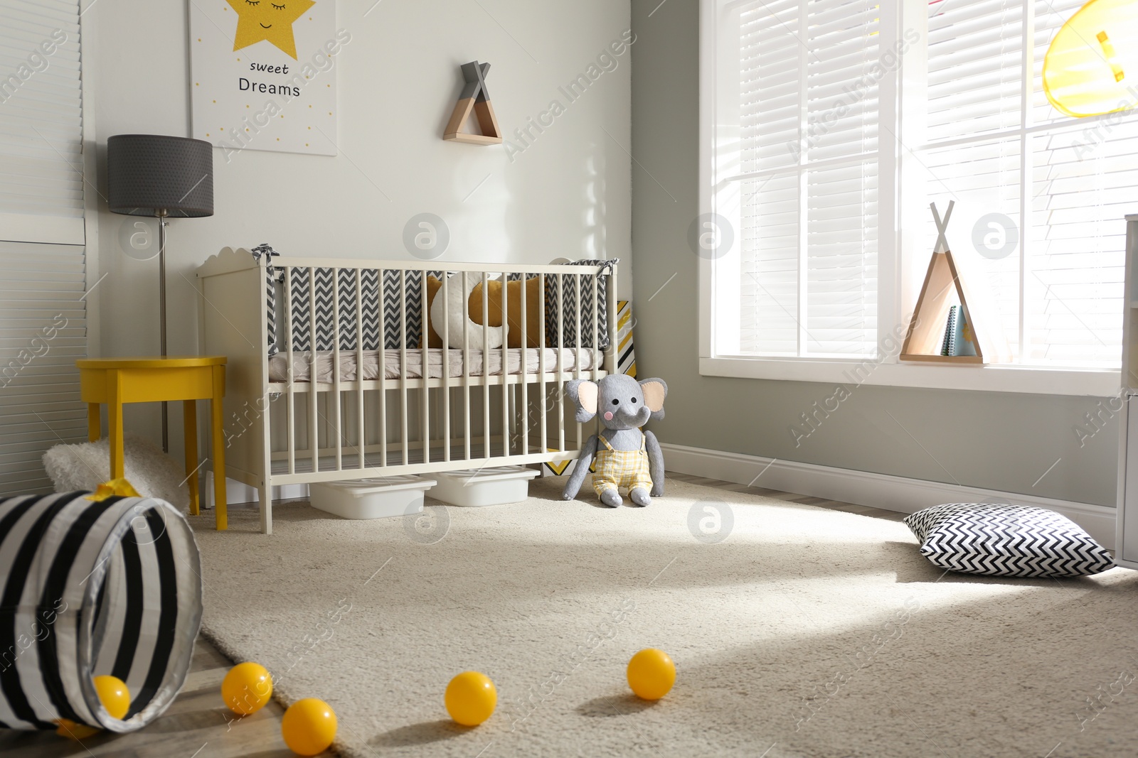 Photo of Cute baby room interior with crib and decor elements