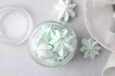 Photo of Tasty meringue cookies in glass jar on light grey table, top view