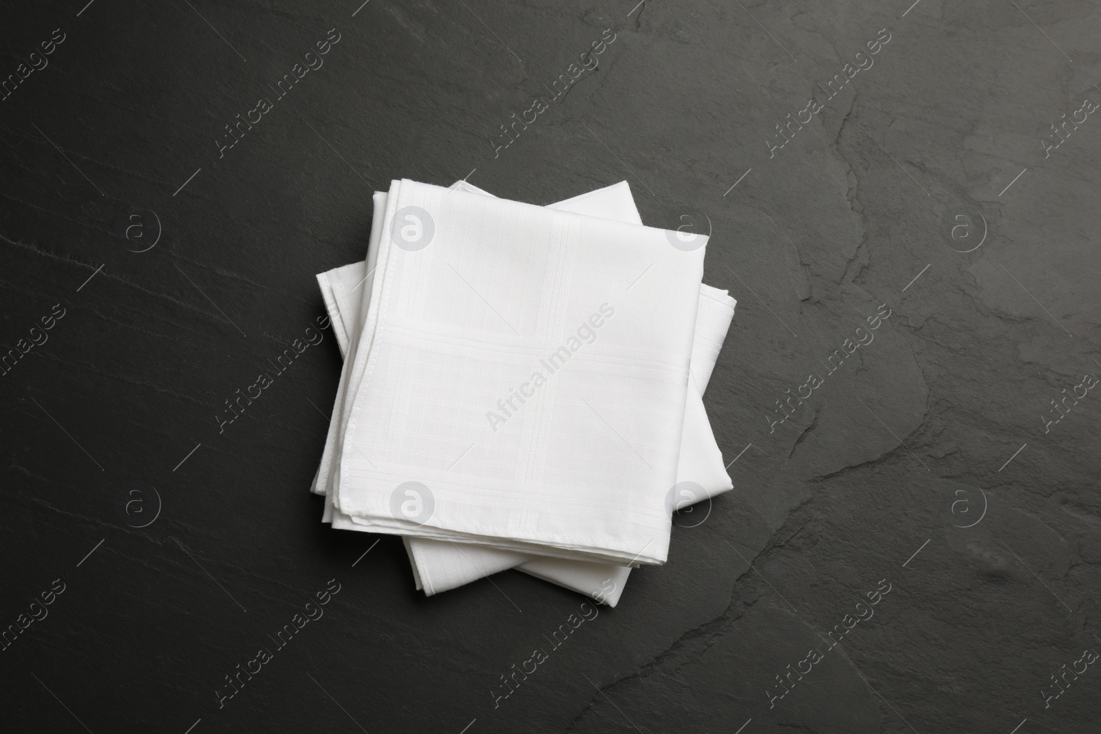 Photo of White handkerchiefs folded on black table, top view