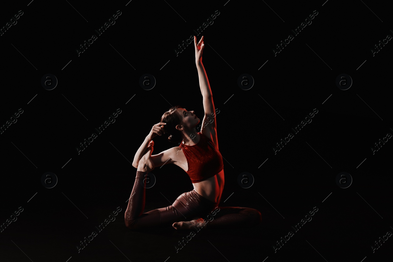 Photo of Young woman performing acrobatic element on stage indoors