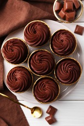 Delicious cupcake and chocolate pieces on white wooden table, flat lay