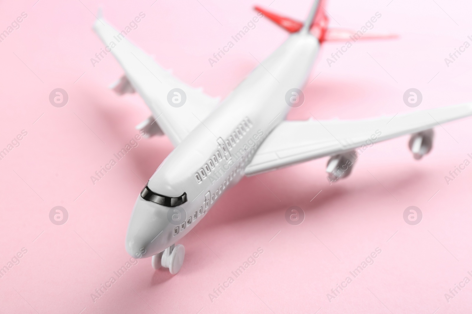 Photo of Toy airplane on pink background, closeup view