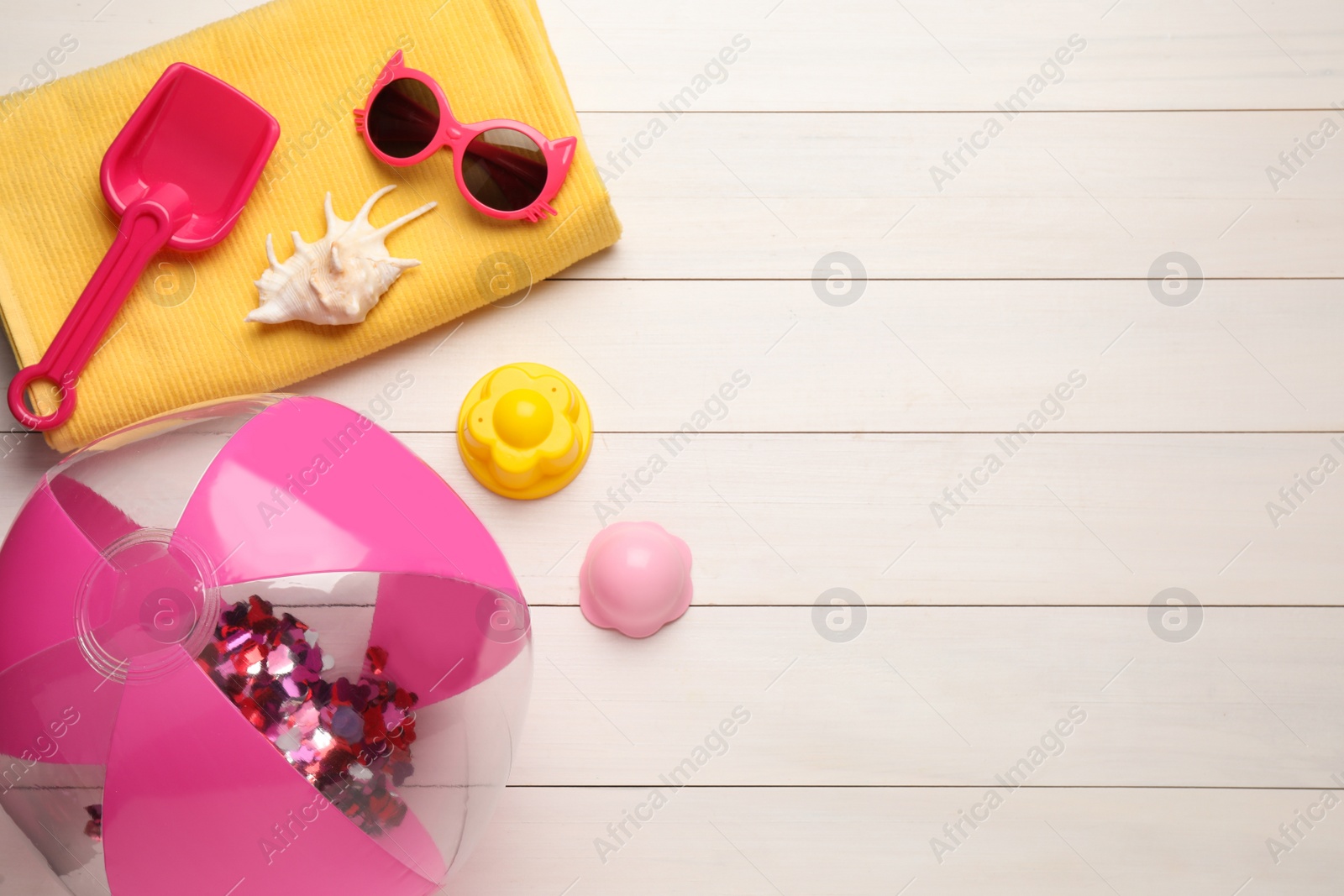 Photo of Beach ball, towel, plastic toys and sunglasses on white wooden background, flat lay. Space for text