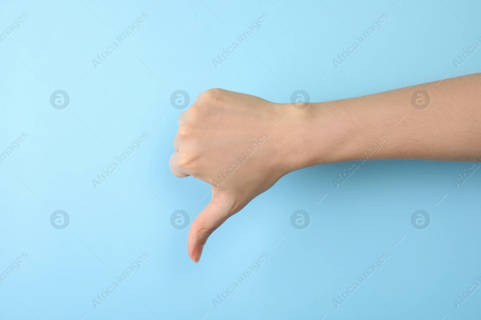 Photo of Woman showing thumb down sign on color background, closeup. Body language