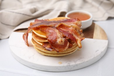 Delicious pancakes with bacon and honey on white table, closeup